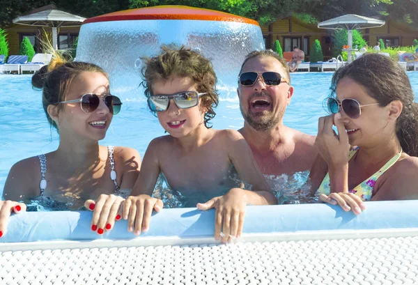 Happy family in pool, having fun in water, mother with three kids enjoying aqua park, beach resort, summer holidays, vacation concept
