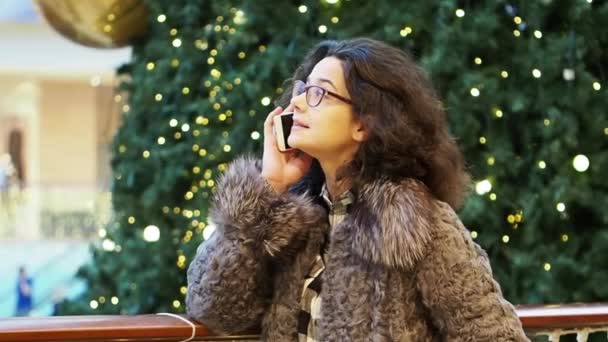 Mladá Kudrnatá Dívka Brýlích Která Mluví Telefonu Rozmazaná Vánoční Stromek — Stock video