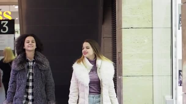 两个穿着冬装的女孩手里拿着购物袋在商场里散步 慢动作 — 图库视频影像
