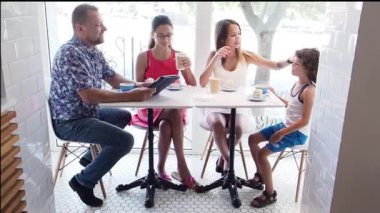 Sevimli mutlu aile kafede kahvaltı yapıyor. İki kızı ve oğlu ile baba kahve dükkanı iç, yavaş hareket eğlenen
