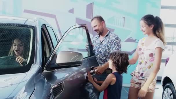 家族は車のショールームで彼女の最初の車を得ることに若い女性を祝福し スローモーション — ストック動画