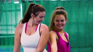 Tenis kortunda eğlenen spor giyimli genç kadınlar, yavaş çekim