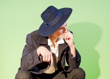 Zarif güzel Latin Amerika mafya mafya casus katil sarkık bir kafa ile, oturan ve hafif bir arka plan üzerinde bir silah tutarak