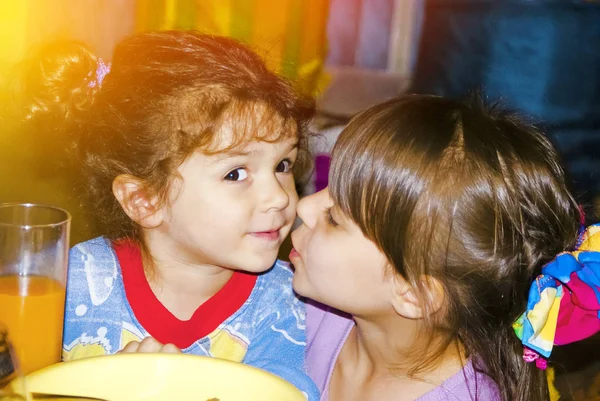 The girl kisses her sister sitting at the festive table. Two Native Sisters Together Forever