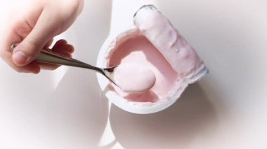 Beyaz arka plan üzerinde meyve yoğurt ile plastik bardak alarak çocuk elleri closeup. Yukarıdan görüntüleyin. Yavaş Çekim