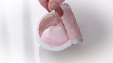 Beyaz arka plan üzerinde meyve yoğurt ile plastik bardak alarak çocuk elleri closeup. Yukarıdan görüntüleyin. Yavaş Çekim