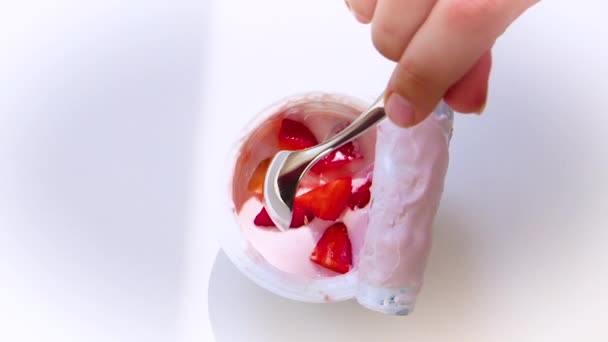 儿童手从塑料杯拿来的白色背景水果酸奶的特写镜头 从上面查看 慢动作 — 图库视频影像