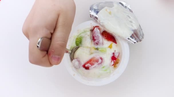 儿童手从塑料杯拿来的白色背景水果酸奶的特写镜头 从上面查看 慢动作 — 图库视频影像