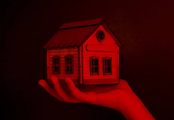 Kleines Spielzeughaus Der Hand Auf Dunkelrotem Hintergrund Das Konzept Der — Stockfoto