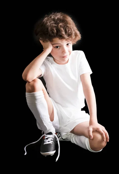 Küçük çocuk futbolcu çizmeler üzerinde çözülmüş dantel ile katta oturan