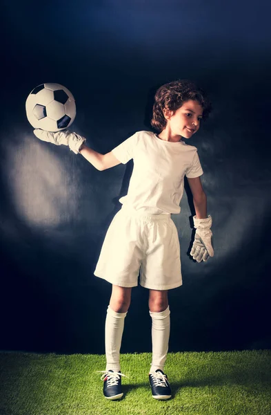 Soccer, action, ball. Boy goalkeeper in football sportswear on stadium pitches the ball hands. Sport concept.