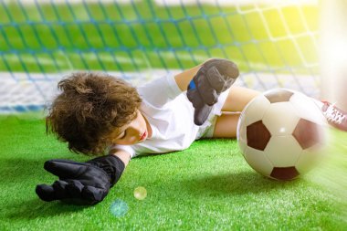Küçük kaleci kalede. Genç futbolcu kaleciyi kurtarmaya çalışıyor. eldiven ile küçük futbol kalecisi