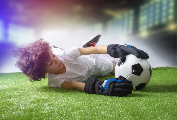 Küçük kaleci kalede. Genç futbolcu kaleciyi kurtarmaya çalışıyor. eldiven ile küçük futbol kalecisi