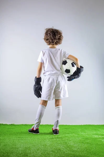 Kid - soccer champion. Boy goalkeeper in football sportswear on stadium with ball. Sport concept.
