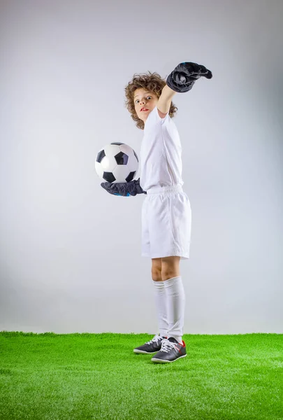 Kid - soccer champion. Boy goalkeeper in football sportswear on stadium with ball. Sport concept.