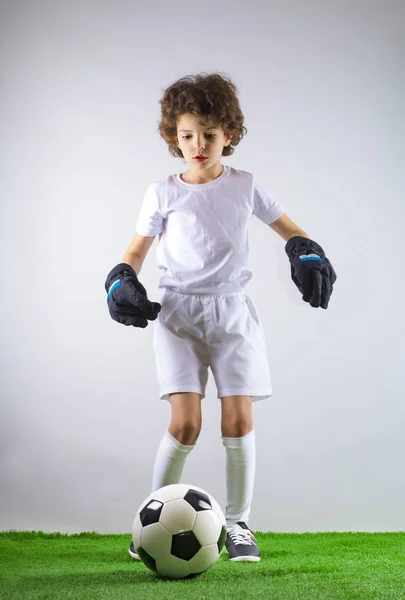 Kid - soccer champion. Boy goalkeeper in football sportswear on stadium with ball. Sport concept.