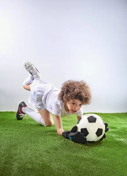 躺在草地上的守门员接住了一个球 兴奋的幼儿在灯光背景下在足球场上踢足球 活跃的童年和运动激情概念 节省空间 — 图库照片