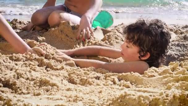 两个姐姐白天和弟弟在沙滩上玩耍 — 图库视频影像