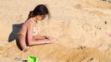 Güzel genç kız kumlu sahilde gündüz eğleniyor. 