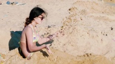 Güzel genç kız kumlu sahilde gündüz eğleniyor. 