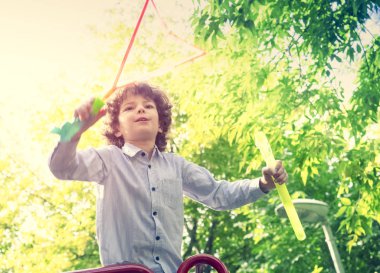 Güneşli bir günde parkta sabun kabarcıkları üfleme çocuk