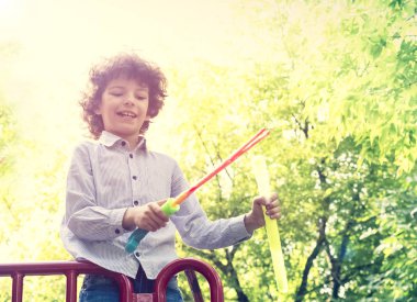 Güneşli bir günde parkta sabun kabarcıkları üfleme çocuk