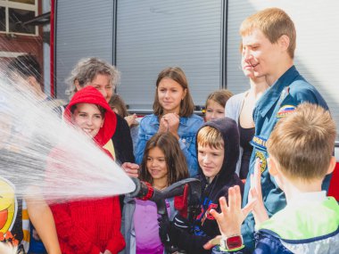 Moskova, Rusya - 07 Ağustos 2019: İtfaiyeci gibi davranan ve su sıçratan mutlu çocuklar. Elinde hortum la bir okul grubunda çocuk ve yetişkin itfaiyeci oynarken.