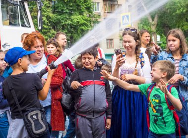 Moskova, Rusya - 07 Ağustos 2019: İtfaiyeci gibi davranan ve su sıçratan mutlu çocuklar. Elinde hortum la bir okul grubunda çocuk ve yetişkin itfaiyeci oynarken.