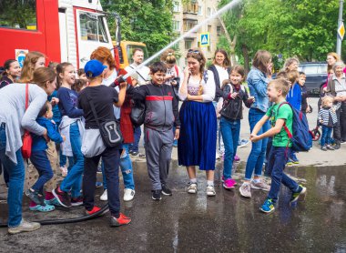 Moskova, Rusya - 07 Ağustos 2019: İtfaiye. İtfaiyeci gibi davranan ve elinde ateş hortumu olan ve su sıçratan mutlu çocuklar. Elinde hortumlu çocuk itfaiyeciyi oynuyor.