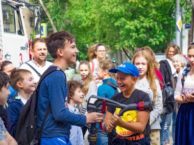 Moskova, Rusya - 07 Ağustos 2019: İtfaiyeci gibi davranan ve su sıçratan mutlu çocuklar. Elinde hortum la bir okul grubunda çocuk ve yetişkin itfaiyeci oynarken.