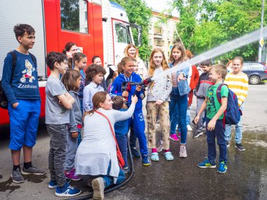 Moskova, Rusya - 07 Ağustos 2019: İtfaiye. İtfaiyeci gibi davranan ve elinde ateş hortumu olan ve su sıçratan mutlu çocuklar. Elinde hortumlu çocuk itfaiyeciyi oynuyor.