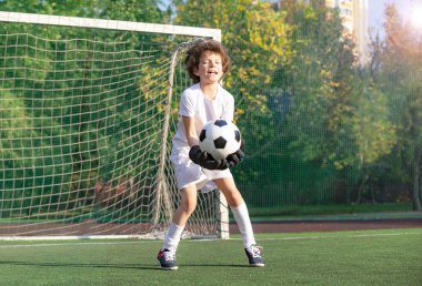 Futbol, aksiyon, top. Çocuk - futbol şampiyonu. Futbol spor giyim erkek kaleci topu ile stadyumda. Spor konsepti.