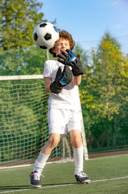 Futbol, aksiyon, top. Çocuk - futbol şampiyonu. Futbol spor giyim erkek kaleci topu ile stadyumda. Spor konsepti.