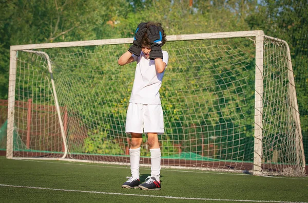 Summer soccer tournament for young kid. Football club. Emotions and joy of game. Young goalie. Kid - soccer champion. Boy goalkeeper in football sportswear on stadium with ball. Sport concept.