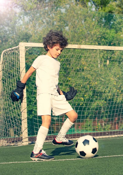 Summer soccer tournament for young kid. Football club. Emotions and joy of game. Young goalie. Kid - soccer champion. Boy goalkeeper in football sportswear on stadium with ball. Sport concept.