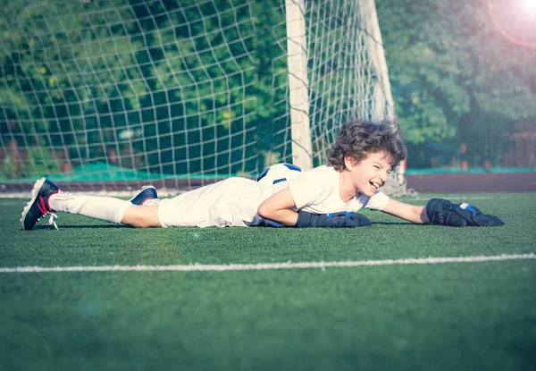 Summer soccer tournament for young kid. Football club. Emotions and joy of game. Young goalie. Kid - soccer champion. Boy goalkeeper in football sportswear on stadium with ball. Sport concept.