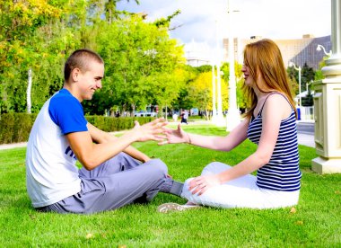 Genç ve sevgi dolu bir çift çimenlerde oturup tatilin tadını çıkarıyor.