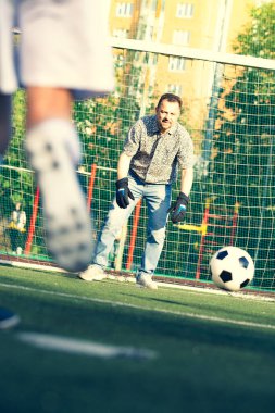 Baba oğlunu futbol oynarken eğitti. Sahada çocuklu bir adam futbol oynuyor. Aile futbolu maçında kalede çocuğa yaklaşmak.