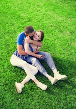 Parkta çimlerin üzerinde oturan romantik iki genç insan. Mutlu görünüyorlar. Yukarıdan görüntüle. 