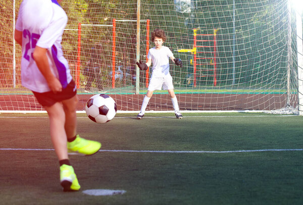 Kids play football on outdoor field. Football pitch. Sports training for player.Goal at the kids soccer match. Selective focus