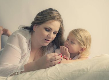 Anne ve kızı pijamalarıyla yatağa uzanıp bir şeyler konuşuyorlar. Aile zamanı.