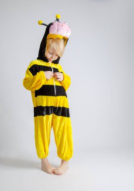 Arı kostümlü, üzgün yüzlü küçük kız beyazı soyutluyor. Boşluğu kopyala