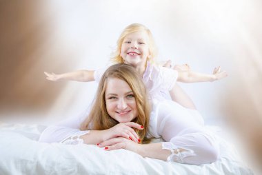 Kilolu anne, sabahları yatakta çocukla oynuyor.