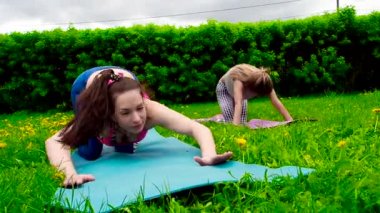 Parktaki yeşil çayır üzerinde egzersiz yapan genç kadınların görüntüleri.