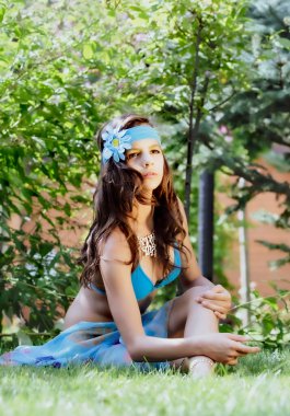 Yeşil çim ve ormanın arka planında mayo giymiş manken görünümlü bir kız. Boşluğu kopyala