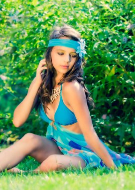 Yeşil çimlerin ve ormanın arka planında mayo giymiş manken görünümlü bir kız..