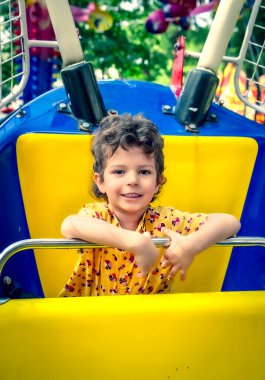 Atlıkarıncaya binen kıvırcık çocuk. Eğlence ve eğlence..