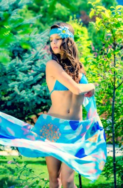 Yeşil çimlerin ve ormanın arka planında mayo giymiş manken görünümlü bir kız..