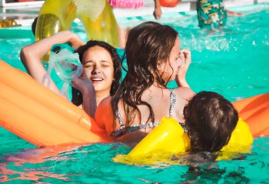 Arkadaşlar yüzme havuzunda havuz yatağıyla eğleniyor.