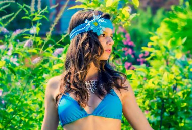 Yeşil çimlerin ve ormanın arka planında mayo giymiş manken görünümlü bir kız..